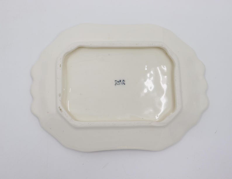 May include: White ceramic butter dish with a scalloped edge. The bottom of the dish has a blue stamp that reads "2418".