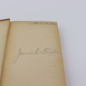May include: A close-up of a book's inside cover with a handwritten inscription that reads "March 6th, 1902" and "Jennie E. Tarplin."