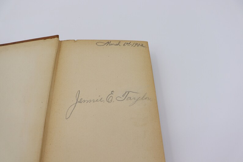 May include: A close-up of a book's inside cover with a handwritten inscription that reads "March 6th, 1902" and "Jennie E. Tarplin."