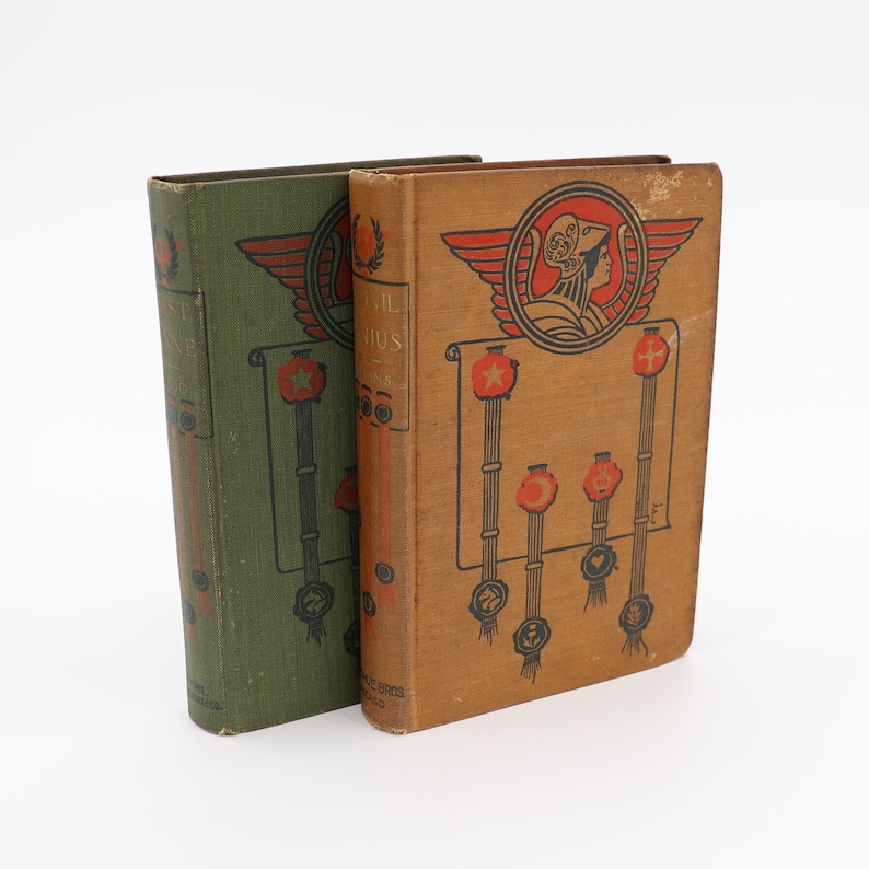 May include: Two vintage hardcover books with green and brown covers. The book on the right has the title "The Trail of Genius" and features a decorative design with a woman's head in a crown and red stars.