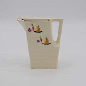 May include: A white ceramic jug with a lid and a handle. The jug features a stylised design of fruit and flowers in red, blue, green and yellow.