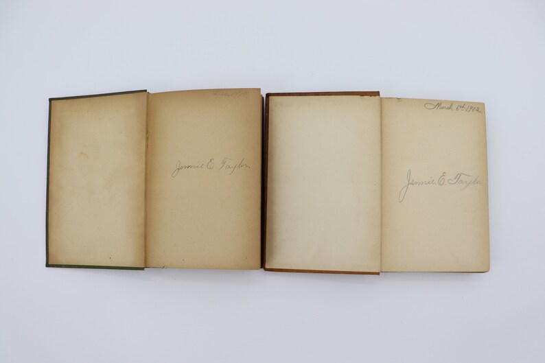 May include: Four vintage books with brown and green covers. The books are open and show blank pages with handwritten signatures. The signatures read "Jennie E. Taylor" and "Mar 6th 1928".