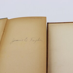 May include: Close-up of the inside cover of a book with a handwritten inscription that reads "Jennie E. Taylor."