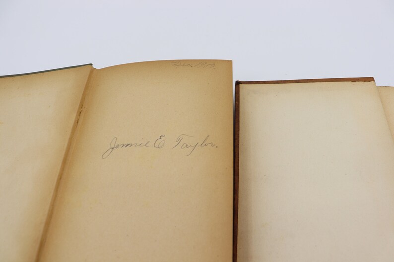 May include: Close-up of the inside cover of a book with a handwritten inscription that reads "Jennie E. Taylor."
