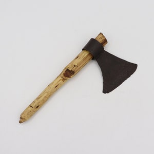 May include: A small, wooden-handled axe with a brown leather wrap near the head. The axe head is made of dark metal and has a slightly curved blade.