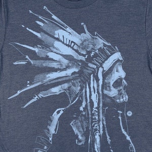 May include: A navy blue t-shirt with a light blue graphic of a Native American wearing a headdress. The graphic is a watercolor style illustration.