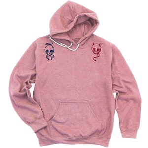 May include: A pink heather hoodie with a skull with angel wings on the left side and a skull with horns on the right side.