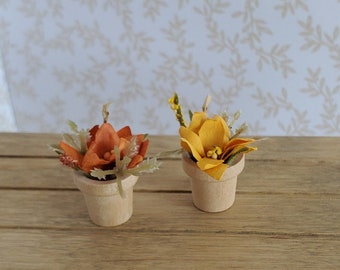 May include: Two small potted plants with artificial flowers. The plant on the left has orange flowers and the plant on the right has yellow flowers. Both plants are in wooden pots.