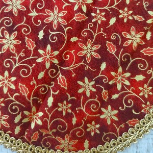 May include: Red fabric with a gold floral pattern. The fabric has a gold trim around the edge.