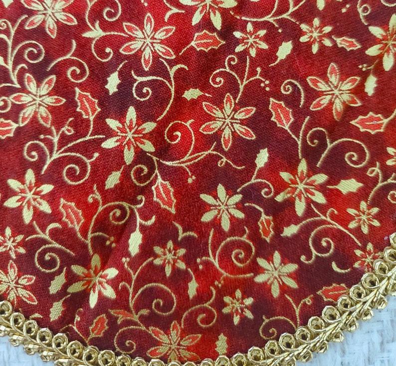 May include: Red fabric with a gold floral pattern. The fabric has a gold trim around the edge.