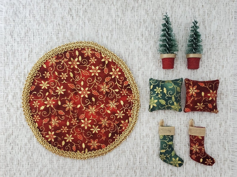 May include: A set of Christmas decorations including a red and gold round table runner, two green and gold pillows, two green and gold stockings, and two small potted green Christmas trees.