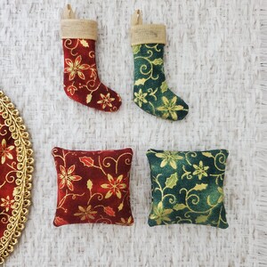 May include: Two small decorative stockings with a red and gold floral pattern and a green and gold floral pattern. Two small square pillows with a red and gold floral pattern and a green and gold floral pattern.