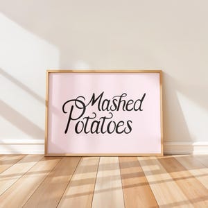 Könnte beinhalten: Ein gerahmter Druck mit rosa Hintergrund und schwarzem Text, der "Mashed Potatoes" lautet.