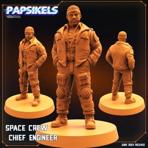 Op de afbeelding: Een 3D-geprint miniatuurfiguur van een persoon die een bruin jack, broek en laarzen draagt. Het figuur staat op een ronde basis. Het figuur is gelabeld "Space Crew Chief Engineer".
