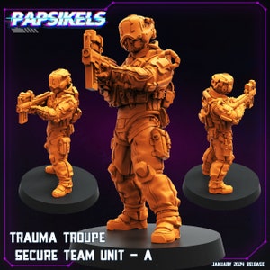 May include: Three orange plastic miniature figures of soldiers wearing futuristic armor and holding weapons. The figures are standing on circular bases. The text "Trauma Troupe Secure Team Unit - A" is at the bottom of the image.