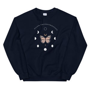 Puede incluir: Sudadera azul marino con un gr&aacute;fico blanco de una mariposa y fases lunares. El texto "ALLOW TRANSFORMATION" est&aacute; escrito en un c&iacute;rculo alrededor de la mariposa.