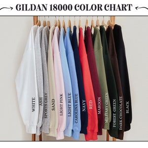 Puede incluir: Una carta de colores de sudaderas Gildan 18000, que muestra 14 colores diferentes, incluyendo blanco, ceniza, gris deportivo, arena, rosa claro, azul claro, azul Carolina, azul marino, rojo, granate, verde militar, verde bosque, chocolate oscuro y negro.