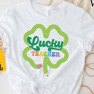 a white t - shirt with a shamrock saying lucky teacher