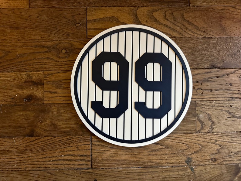 May include: A white and blue circular sign with a baseball field pattern and the number 99 in black.