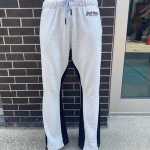 Puede incluir: Pantalones de chándal grises con paneles laterales negros y un logotipo que dice "Search & Rescue" con el texto "Dive Deeper" debajo.