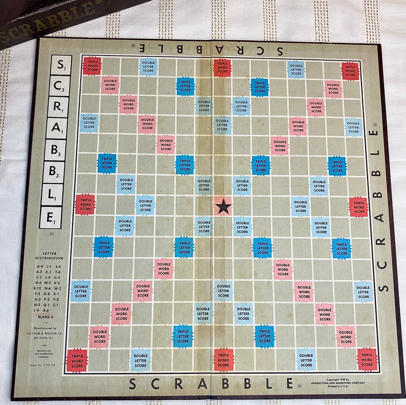 May include: A vintage Scrabble game board with a star in the center. The board is made of a light brown material and has a grid of squares. Each square has a different color and a label indicating the score multiplier for that square. The labels include "Double Letter Score", "Triple Letter Score", "Double Word Score", and "Triple Word Score".