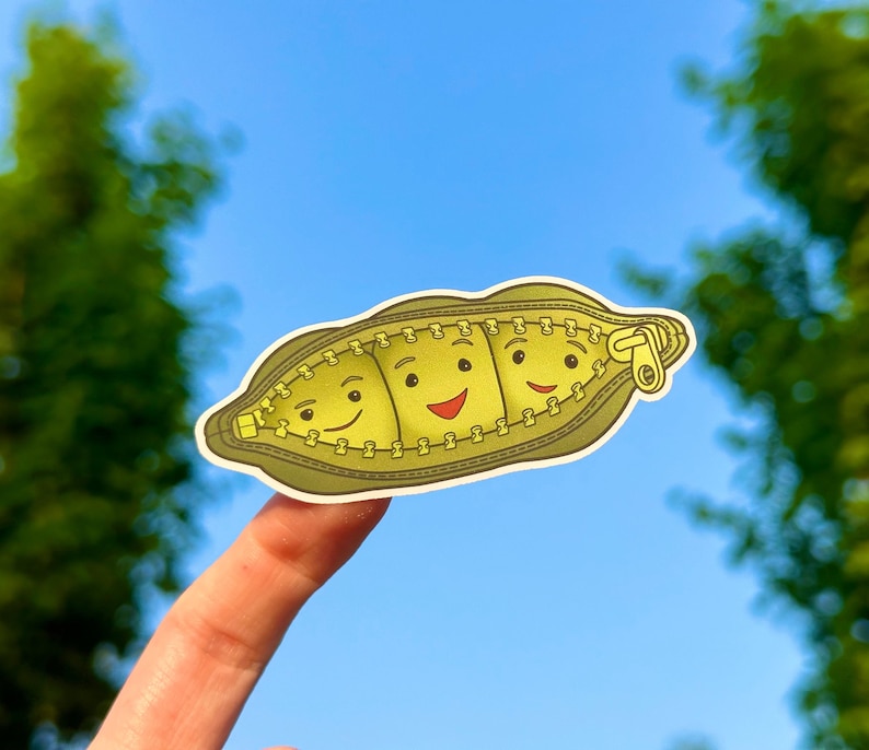 May include: A green zippered pouch with three smiling faces. The pouch is made of fabric and has a zipper closure.