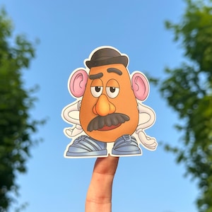 May include: A cartoon sticker of Mr. Potato Head wearing a black hat and blue shoes. He has a brown potato body, a brown mustache, and a brown nose.