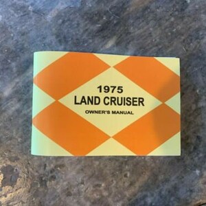 May include: A vintage 1975 Land Cruiser owner's manual. The cover is light green with a pattern of orange diamonds. The text "1975 LAND CRUISER OWNER'S MANUAL" is printed in black.