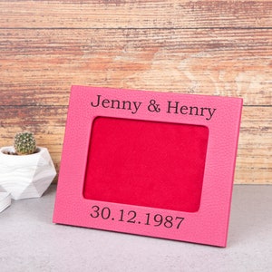 Könnte beinhalten: Rosafarbener Leder-Bilderrahmen mit roter Passepartout und personalisiertem Text "Jenny & Henry 30.12.1987".