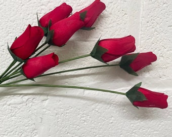 May include: A bouquet of red wooden roses with green stems and leaves.