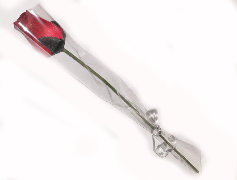 May include: A single red rose with a black stripe wrapped in clear plastic and tied with a silver ribbon.