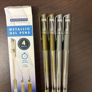 May include: A 4-pack of Kensington Stationery metallic gel pens. The box is white and blue with the text "Metallic Gel Pens" and "4 Pack". Four pens with gold and silver metallic ink are visible, with clear barrels and 0.5mm fine tips.
