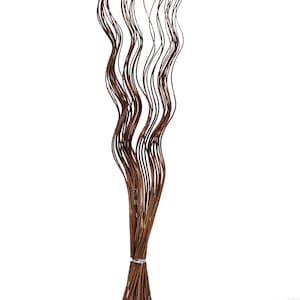 May include: A bunch of brown willow branches with a wavy, curly shape. The branches are tied together at the bottom.