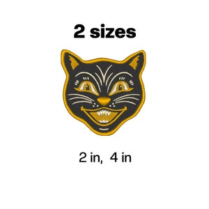 May include: Embroidered black cat face with gold detailing and outline. The cat has a wide, grinning mouth. Text reads "2 sizes" with size options of 5 cm and 10 cm.