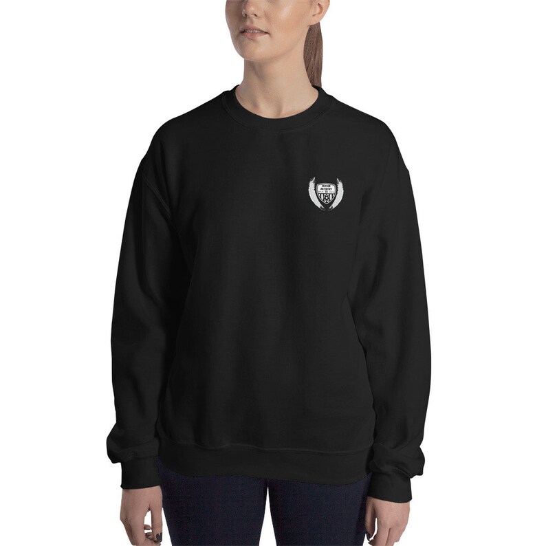 May include: Black sweatshirt with a white embroidered logo on the left chest. The logo is a shield with wings and the text "Never Give Up" inside the shield.