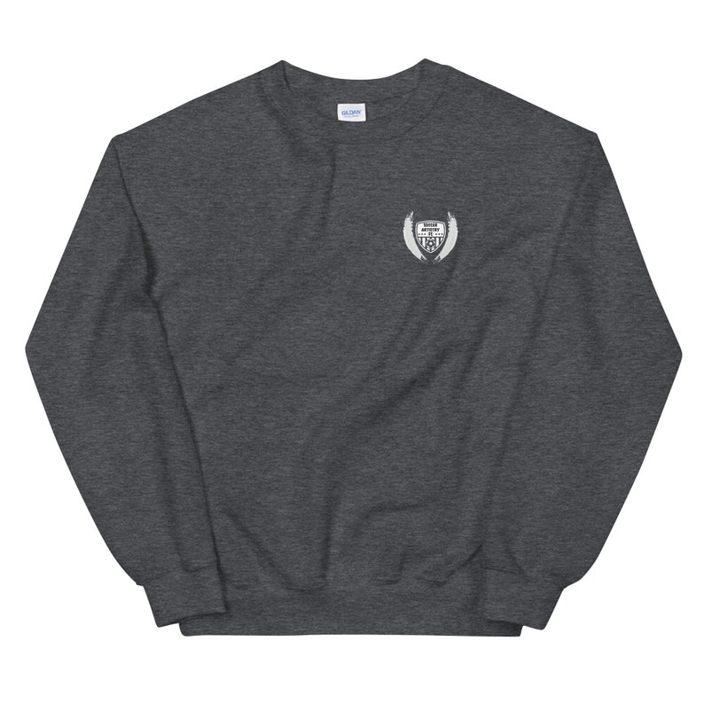 May include: A dark gray sweatshirt with a white embroidered patch on the left chest. The patch features a shield with wings and the text "Never Give Up The Fight".