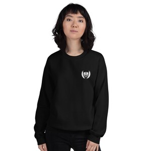 May include: Black sweatshirt with a white embroidered logo featuring a shield with the text "Protect Your Tribe" inside. The shield is surrounded by wings.