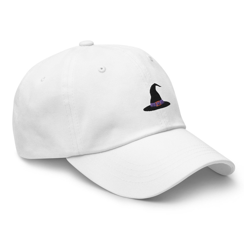 May include: White baseball cap with a black embroidered witch hat with a purple and orange band.