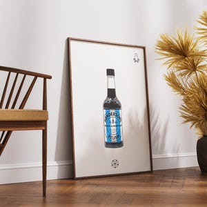 May include: A framed print of a bottle of Henderson's Relish, a dark brown sauce with a blue and white label. The bottle is on a white background with a black and white design in the bottom corner.