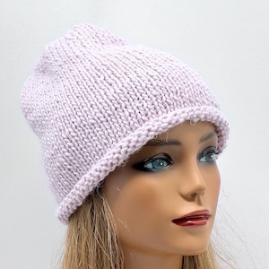 May include: A light purple knitted beanie hat with a folded brim. The hat is made of a soft, textured yarn and is perfect for keeping warm in the winter.