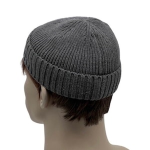 May include: A gray knitted beanie with a folded brim. The beanie is made of a soft, comfortable material and has a classic look.