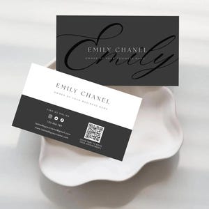 Könnte beinhalten: Zwei rechteckige Visitenkarten in Schwarz-Weiß-Optik. Eine Karte ist dunkelgrau mit dem in schwarzer Schreibschrift gedruckten Namen Emily Chanel. Die andere Karte ist weiß und dunkelgrau mit dem Namen Emily Chanel, Kontaktdaten und einem QR-Code.