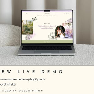 May include: A laptop computer displaying a website for a shop selling notebook covers, sleeves, and enamel keychains. The website features a floral design and a butterfly graphic. The text on the website reads "Notebook cover sleeves & enamel keychains" and "Our Story".
