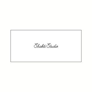 Op de afbeelding: Een witte rechthoekige kaart met de woorden "Shakti Studio" in elegant, cursief zwart schrift. De tekst is gecentreerd in de rechthoek, die is omlijnd door een dunne zwarte rand.