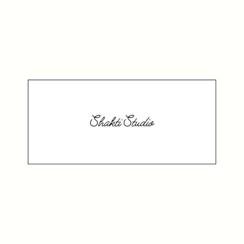 Op de afbeelding: Een witte rechthoekige kaart met de woorden "Shakti Studio" in elegant, cursief zwart schrift. De tekst is gecentreerd in de rechthoek, die is omlijnd door een dunne zwarte rand.