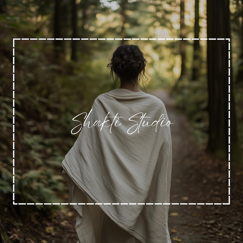 May include: A person walking away on a forest path, wearing a cream-colored shawl. The text "Shakti Studio" is written in cursive across the shawl. The background is a blurred view of a forest with tall trees.