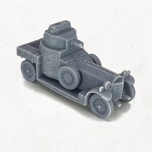 May include: A gray, detailed model of an armored car with a turret on top. The model is made of plastic and has a realistic design.
