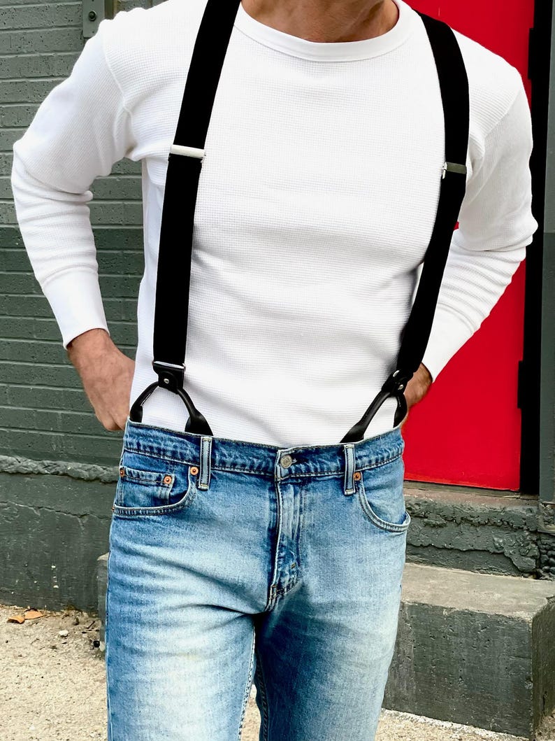Handmade black linen button-on suspenders for men, styled with denim jeans and a white waffle knit shirt. Classic and rugged groomsmen suspenders for weddings, vintage menswear, and timeless formal fashion. Ethically crafted in Texas, USA by Stratton Suspender Co.