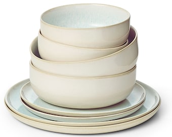 May include: A stack of four light blue and cream ceramic bowls with a light blue and cream ceramic plate underneath.