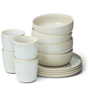 Può includere: Un set di stoviglie in ceramica di colore grigio chiaro. Il set comprende ciotole, piatti e tazze.